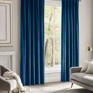 Vue d'ensemble d'un salon élégant avec une grande fenêtre habillée de longs rideaux en velours bleu canard, un canapé gris et une lampe sur pied dorée.