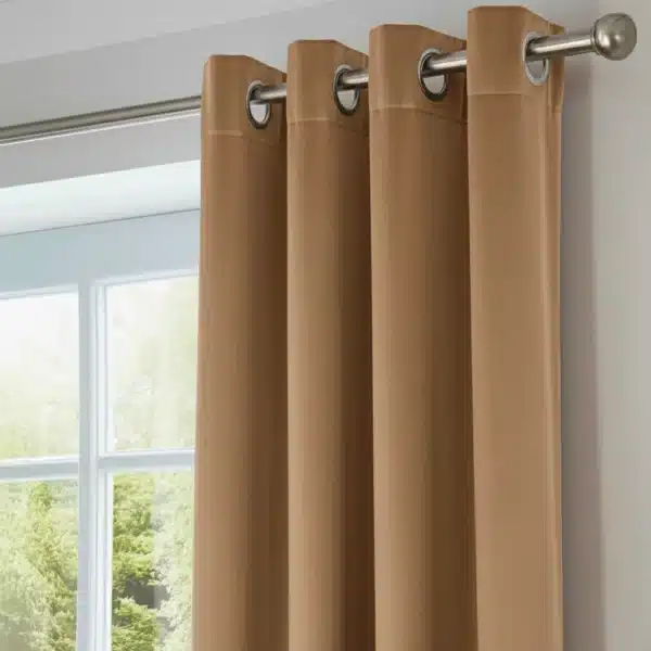 Gros plan sur des rideaux en tissu de couleur rouille ou brun noisette, montrant le tissu, les plis et les œillets métalliques argentés sur une tringle.