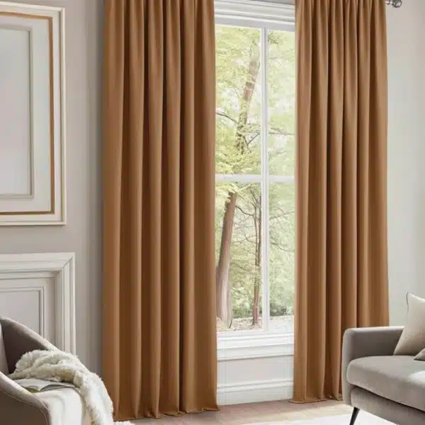 Rideaux couleur rouille ou brun noisette, plissés, suspendus à une tringle cachée dans un salon élégant avec des meubles gris et une lumière dorée.