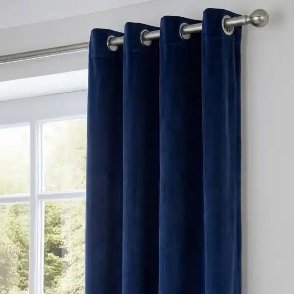 Gros plan montrant la texture soyeuse du velours bleu nuit et la finition des œillets métalliques sur la tringle.