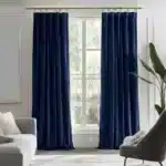 Grand salon moderne décoré avec une paire de rideaux en velours bleu nuit profond sur une tringle dorée.