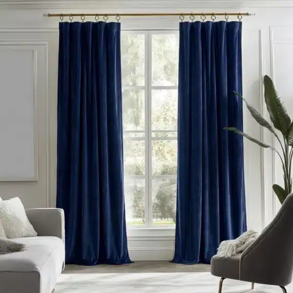 Grand salon moderne décoré avec une paire de rideaux en velours bleu nuit profond sur une tringle dorée.