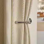 Détail du rideau isolant thermique et phonique beige près d’une poignée de porte, montrant la texture et l’épaisseur du tissu.