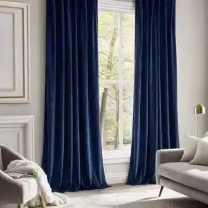Fenêtre haute habillée de longs rideaux en velours couleur bleu nuit, apportant une touche cosy et chic à la pièce.