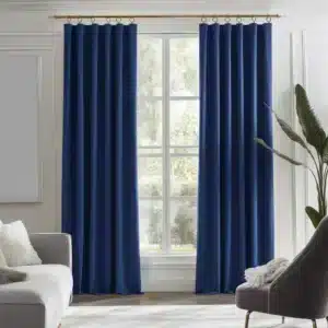 Paire de longs rideaux en velours bleu roi avec anneaux ou œillets visibles, suspendus dans un salon lumineux.
